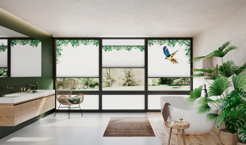 Weiße Plissees mit einem Design an einer Fensterfront bedruckt mit Blattmustern und einem Papagei.