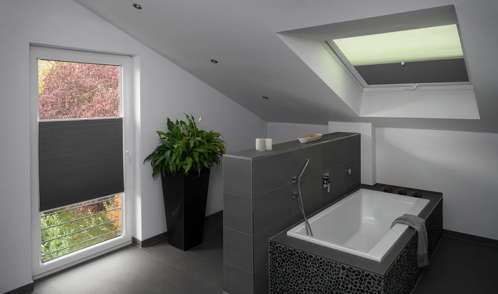 Dunkelgraue Plissees halten zuverlässig Sonne in einem Badezimmer mit dunkelgrauen Akzenten ab.