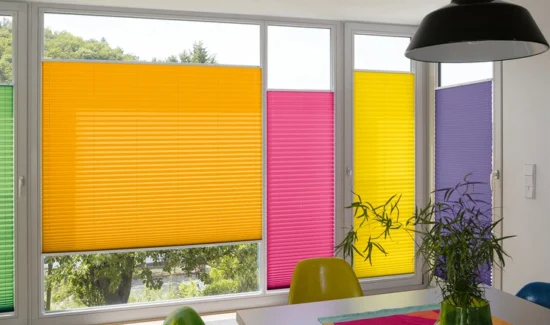 Verschiedenfarbene Plissees beschatten aneinanderliegende Fenster verschiedener Größen.