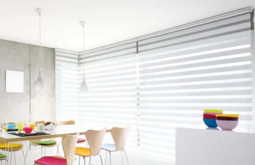 Ein Esszimmer mit buntem Geschirr und Doppelrollos.