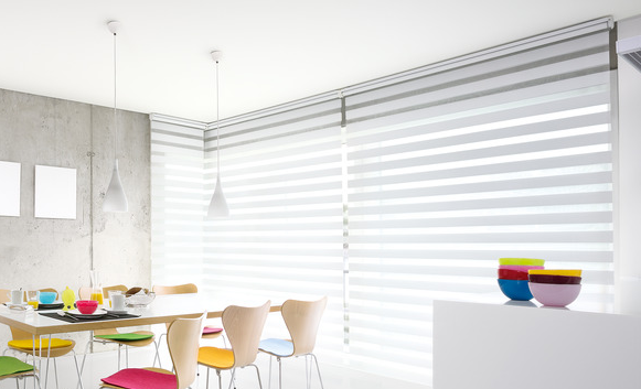 Ein Esszimmer mit buntem Geschirr und Doppelrollos.