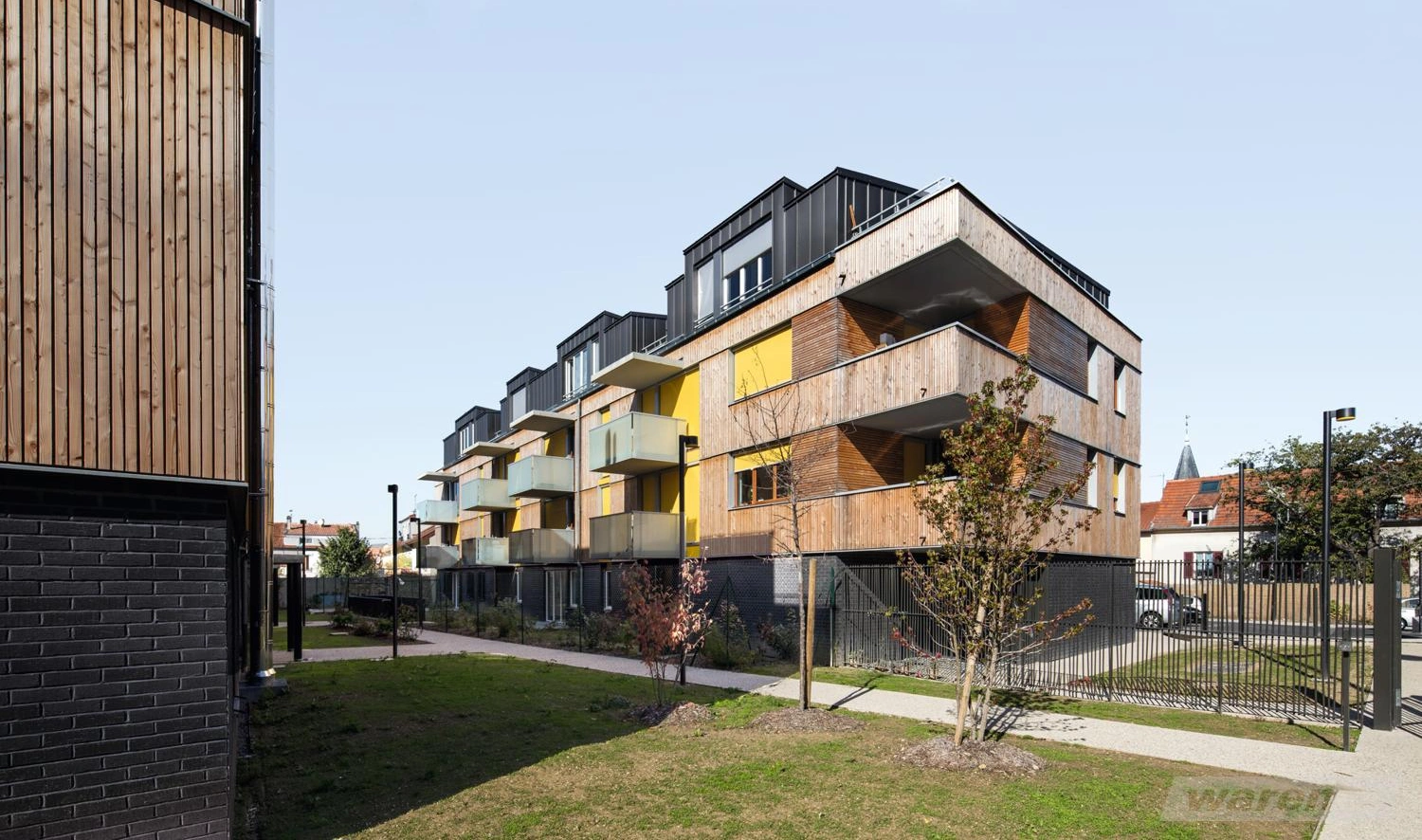 Mehrparteienhäuser mit Holzverkleidung und verschiedenen Fassadenfarben.