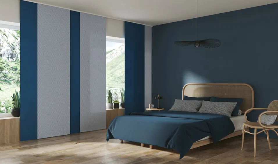 Ein minimalistisches Schlafzimmer mit Blautönen und passenden Flächenvorhängen abwechselnd in blau und grau.