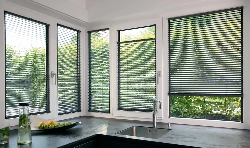 Stilvolle graue Jalousien beschatten eine moderne Küchenzeile.