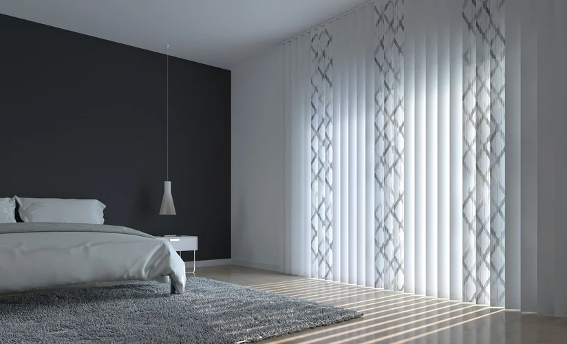 In einem schlichten modernen Schlafzimmer hängt eine weiße Vertikaljalousie mit grauen Mustern.